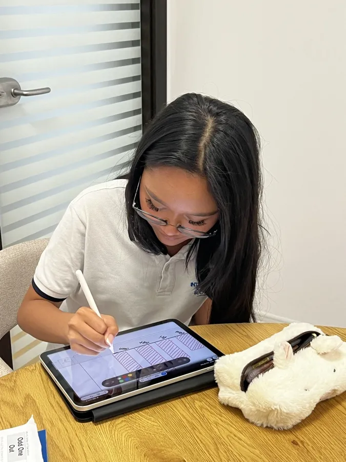 Kinan working on her tablet at a round oak table at Pebble House