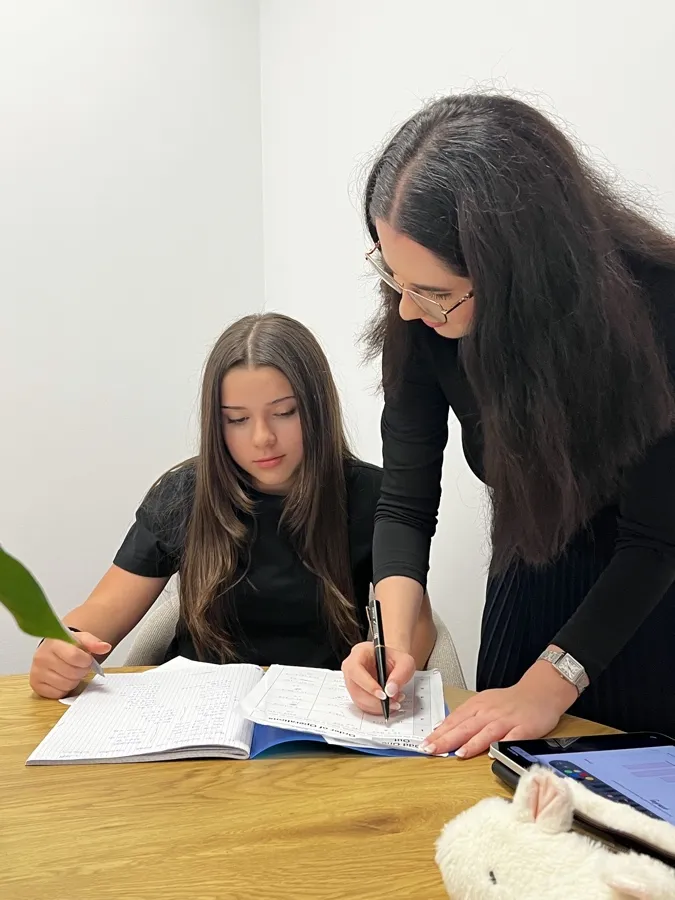 Ms Patricia explaining a worksheet to Yasemin at an oak table