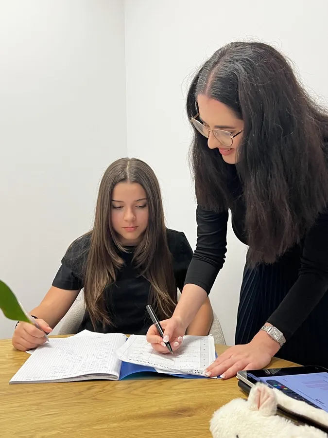 Ms Patricia writing out a step beside Yasemin at an oak table